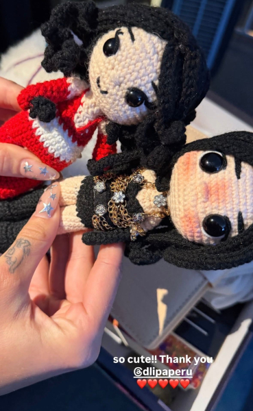 Dua Lipa holding crocheted dolls with a star manicure